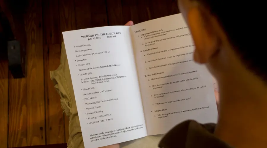 A worshipper reading the Sunday bulletin